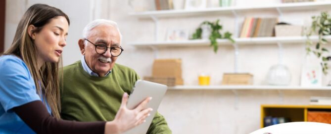 Home caregiver assisting senior man to use telehealth and senior care